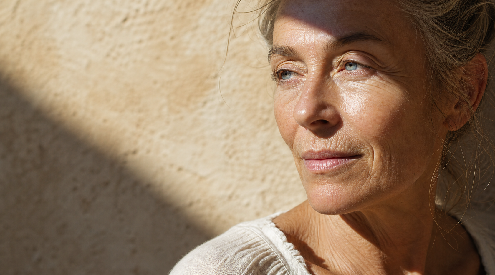 Rostro de una mujer adulta atravesado por luz solar y sombra protectora